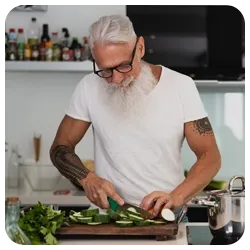 A bearded man chopping vegetables in his kitchen