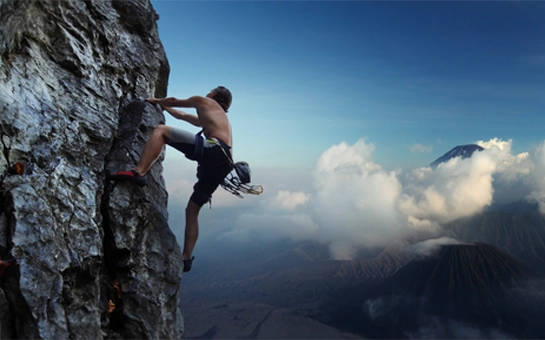 A man rock climbing high on a mountain range
