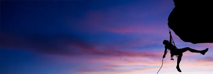 An individual rock climbing at sunset